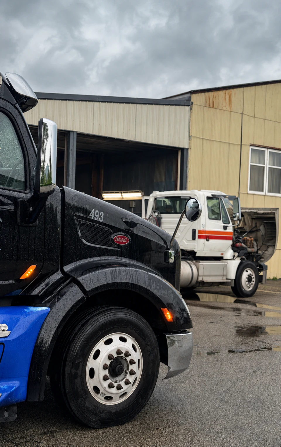 Black and blue Peterbilt truck 493 outside Big Truck & Trailer Repair in Park City, Illinois, with a white service truck behind it